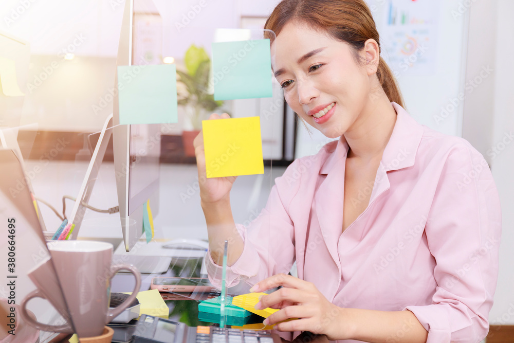 Close up business start up successful smile woman writing note on post-it at office. Businesswoman brainstorm writing note on blue post note and sticky note. Close up business start up successful smile woman writing note on post-it at office. Businesswoman brainstorm writing note on blue post note and sticky note.