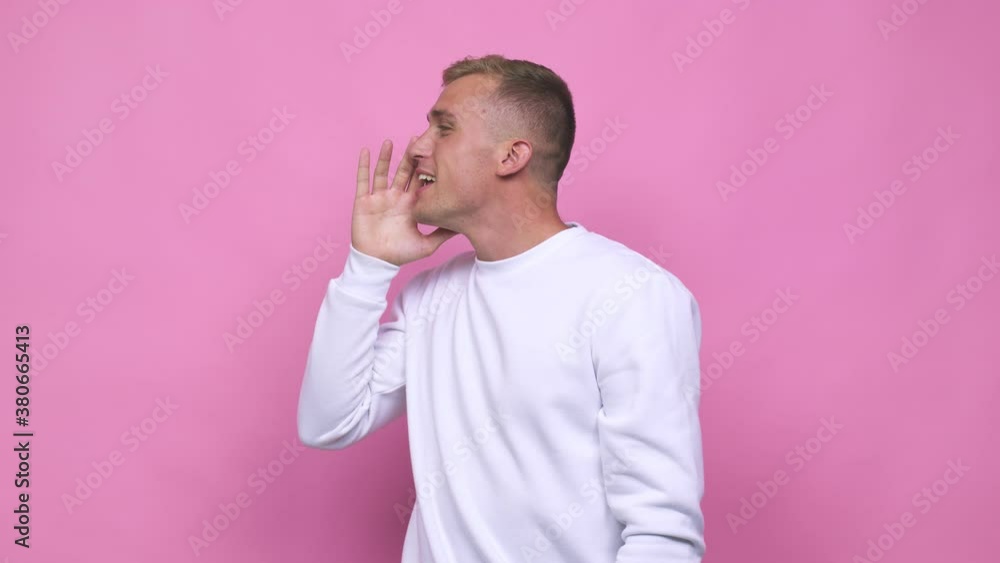 Young caucasian man shouting and holding palm near opened mouth Young caucasian man shouting and holding palm near opened mouth
