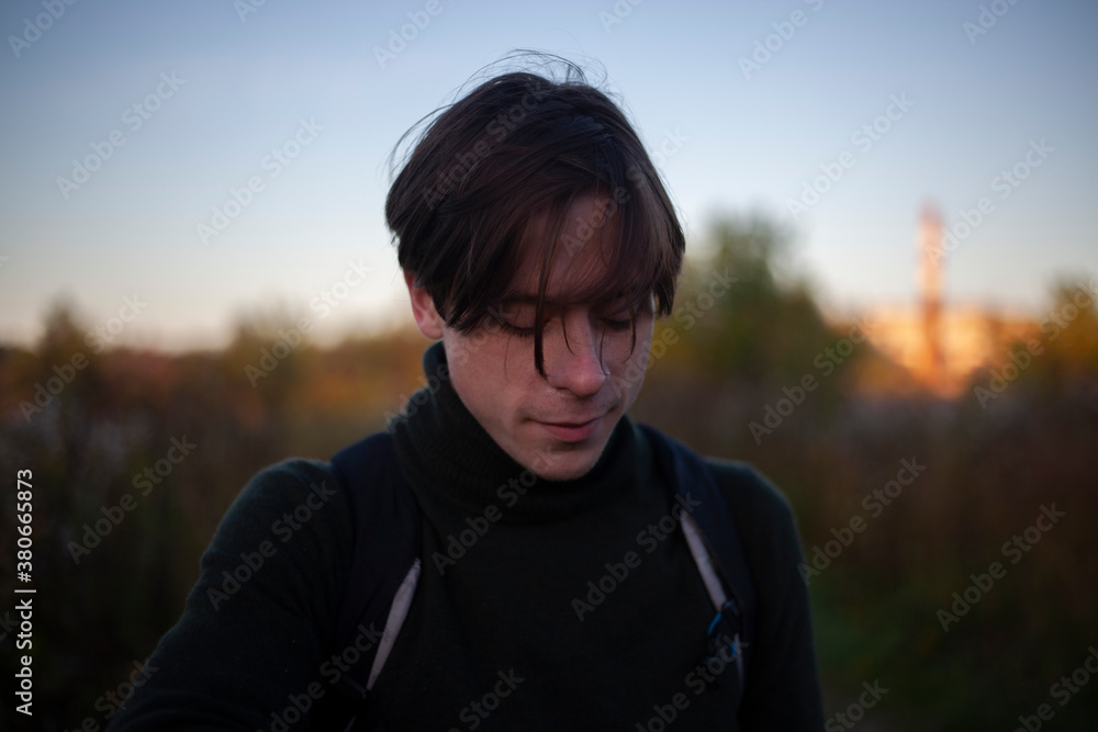 Portrait of a guy in the sunlight. Young man in nature. A student is skipping school in the woods. A guy with a regular haircut. A young man of European appearance. A man on a summer day.