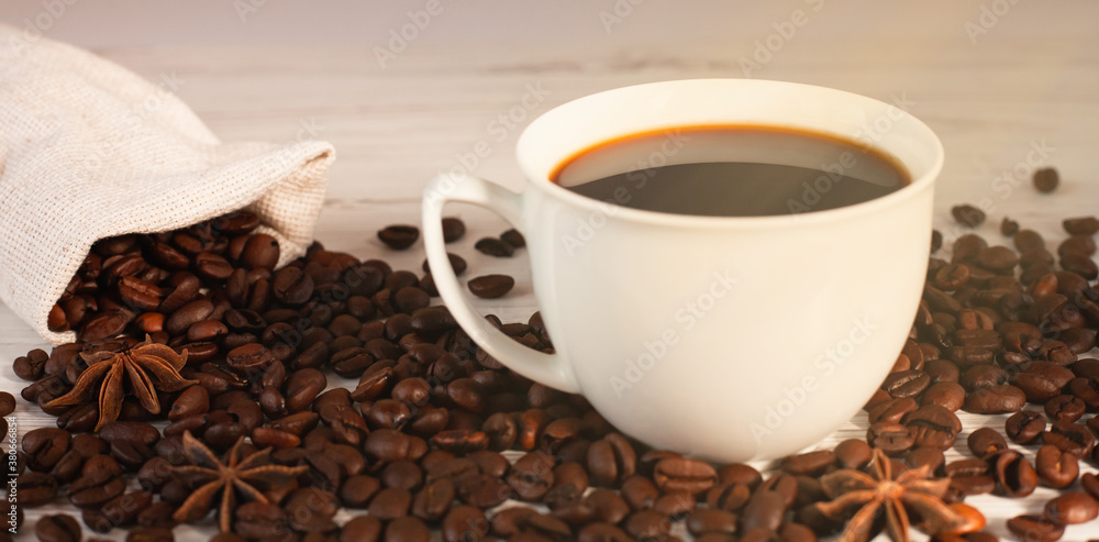 Cup of coffee and coffee beans on wooden background. Close-up.