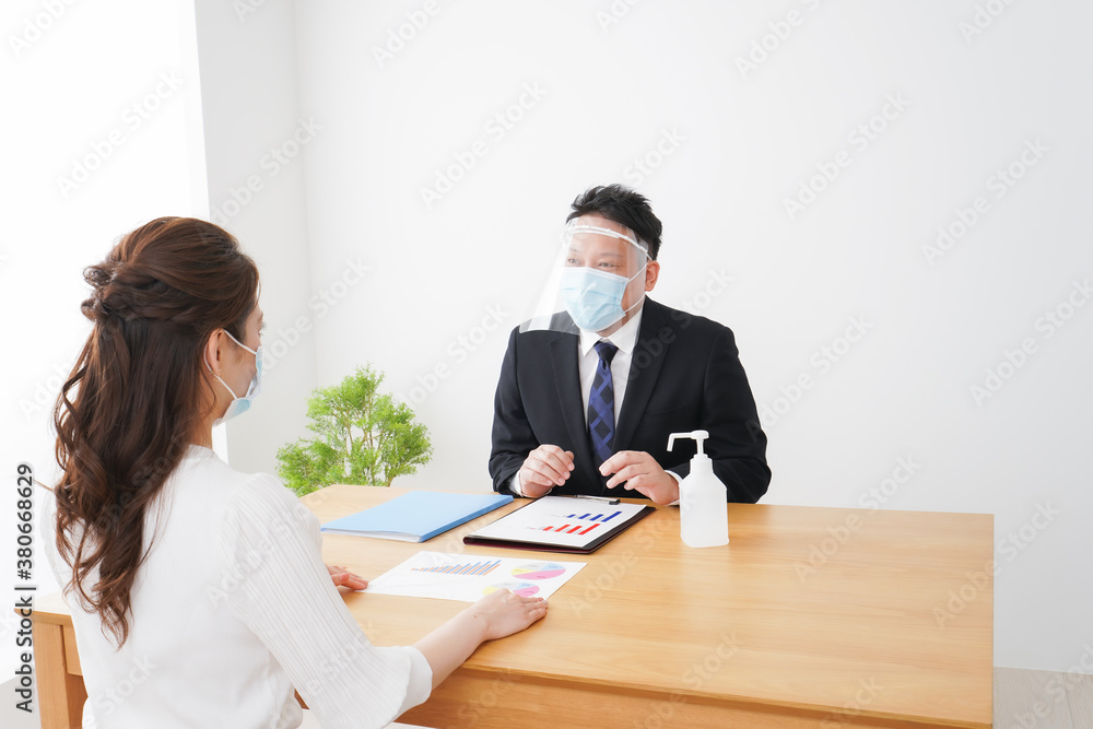 フェイスシールドとマスクをして商談をするビジネスパーソン フェイスシールドとマスクをして商談をするビジネスパーソン
