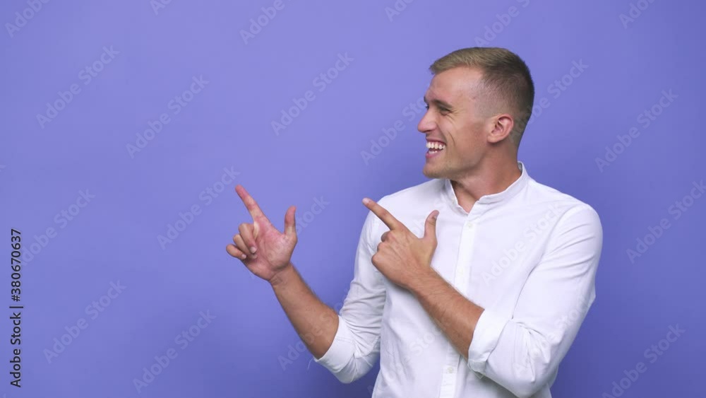 Young caucasian man pointing with forefingers to a copy space, expressing excitement and desire Young caucasian man pointing with forefingers to a copy space, expressing excitement and desire