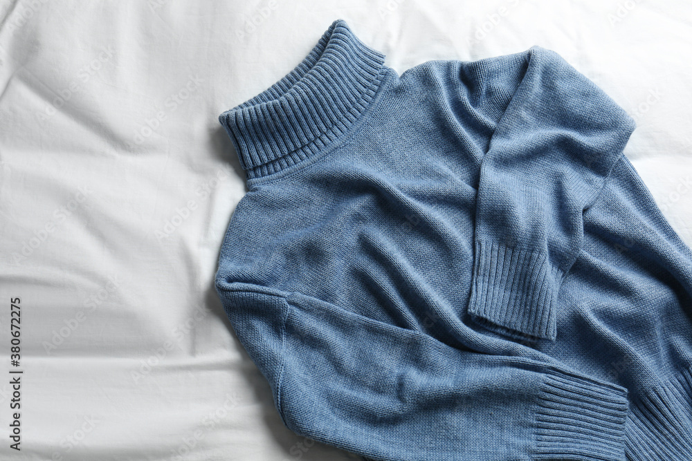 Stylish knitted sweater on white fabric, top view Stylish knitted sweater on white fabric, top view