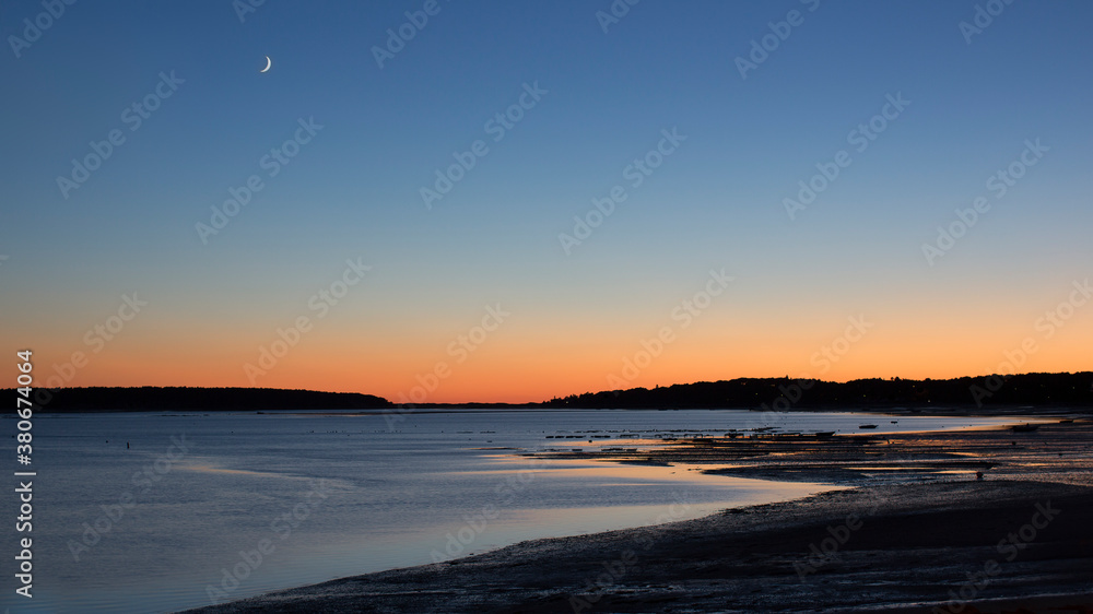 A gorgeous sun set and cresent moon over the bay and oyster beds in Cape Cod 