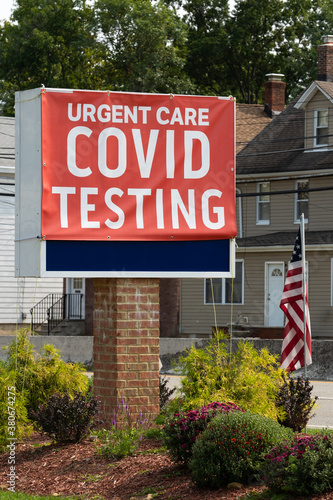 sign at a covid testing site with white lettering on a red sign with the United States flag beside it