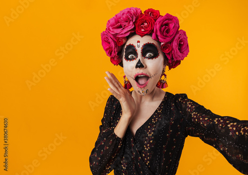 Image of girl in halloween makeup and flower wreath taking selfie photo