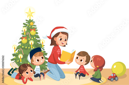 Young mother babysitter reading a book to kids at Christmas tree on Christmas Eve. Children in a kinder garden. Children listening to the teacher.