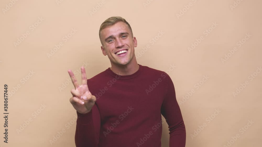 Young caucasian man showing victory sign and smiling broadly Young caucasian man showing victory sign and smiling broadly
