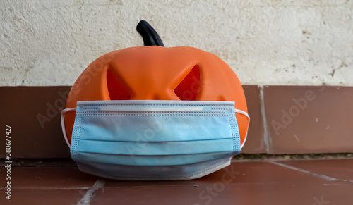 Halloween pumpkin with a protective medical mask on a white background. Halloween symbol 2020