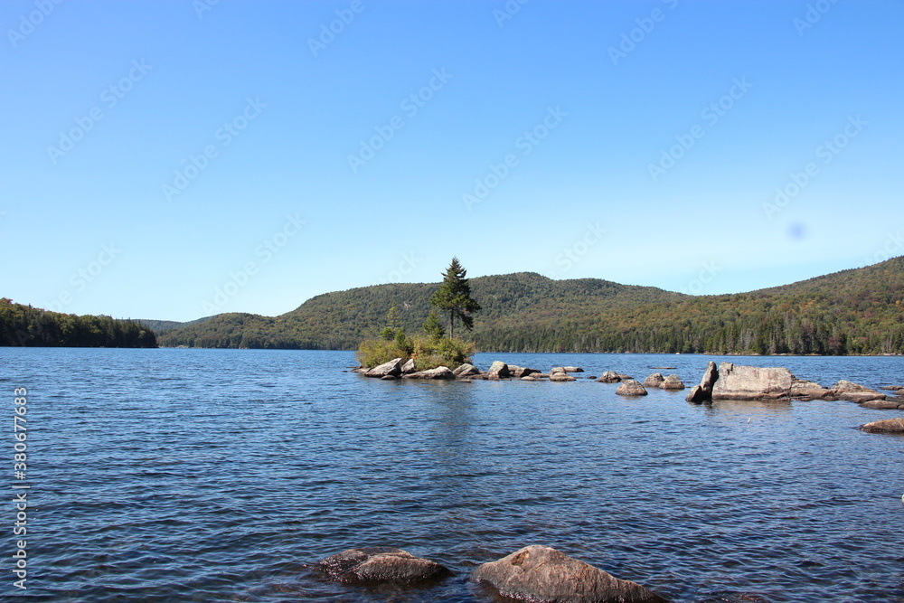 Naklejka premium Adirondack lake with island containing rocks and trees