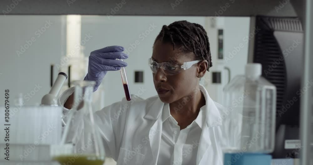 Female Laboratory Scientist Conducts Experiment in Science lab looking at blood sample with Coronavirus