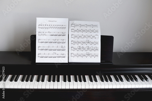 Empty black piano with notes in front of white wall