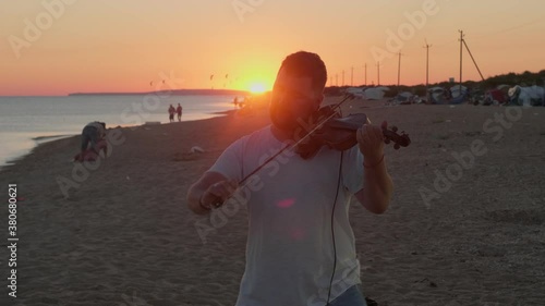 Violinist plays the violin on the beach during wonderful sunrise. Eye angle view