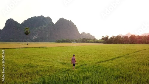 Traveler is walking through a rice paddy in Myanmar. This clip was taken by a drone. photo