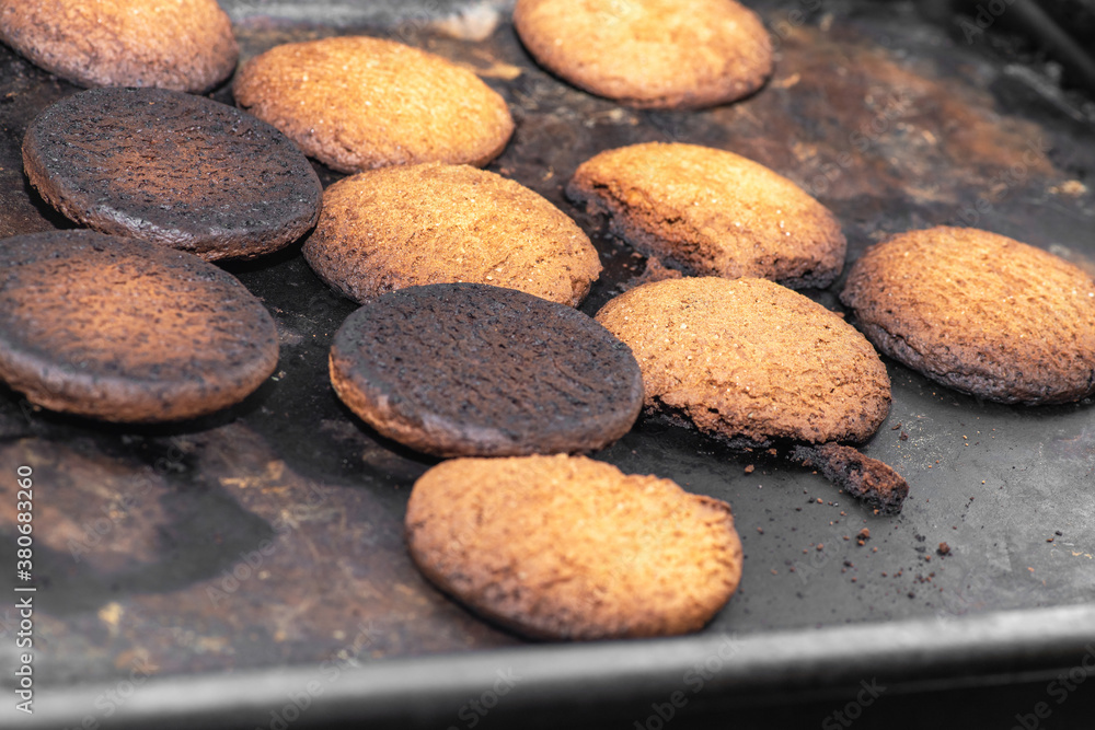 Burnt cookies. Burnt, burnt oatmeal cookies lie on a black baking sheet. Vertical photo Burnt cookies. Burnt, burnt oatmeal cookies lie on a black baking sheet. Vertical photo