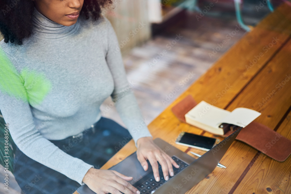 Crop anonymous black woman typing on netbook in workplace Crop anonymous black woman typing on netbook in workplace
