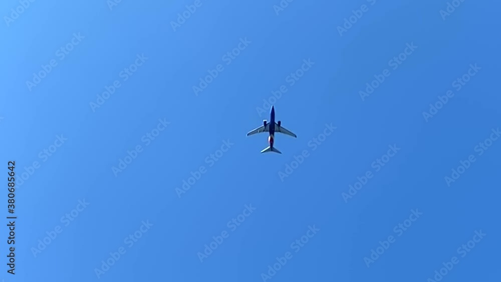 Airplane flying overhead, view beneath aircraft in sky Airplane flying overhead, view beneath aircraft in sky