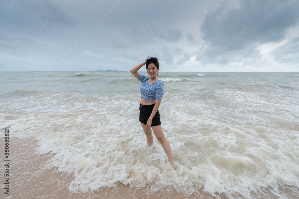 Asian beautiful girl has felt happy on the beach with a cloudy sky.