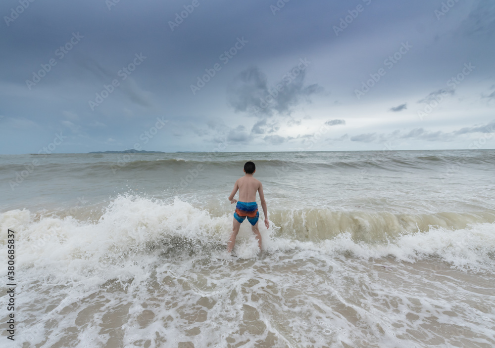 An Asian boy has felt happy and fun on the beach with a cloudy sky. An Asian boy has felt happy and fun on the beach with a cloudy sky.