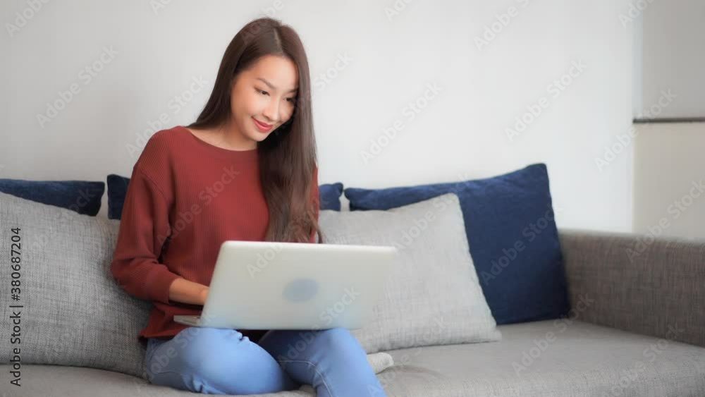Asian woman using her laptop computer sitting on the bed, she is typing on the laptop keyboard and suddenly wins the prize, lottery, exited face expression, raise hands up Asian woman using her laptop computer sitting on the bed, she is typing on the laptop keyboard and suddenly wins the prize, lottery, exited face expression, raise hands up