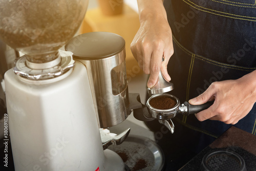Hand of barista man holding coffee tamper with grind coffee for making coffee for customers
