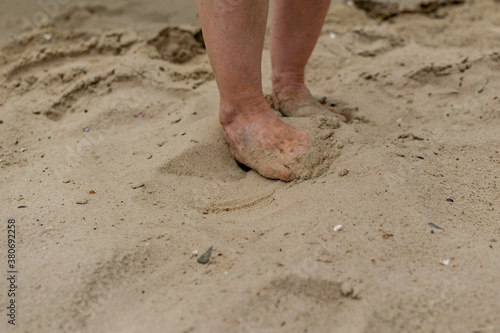 Feet naked barefoot without shoes burrow in the sand on a sandy beach, white skin and toes make movements