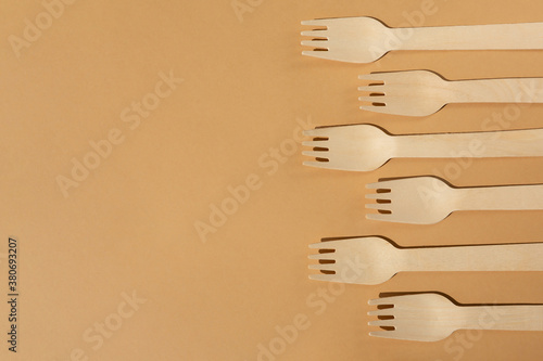 Wooden forks on a beige or brown background. Contrast lighting. Flat lay. Eco friendly wooden cutlery. Plastic Free Concept.