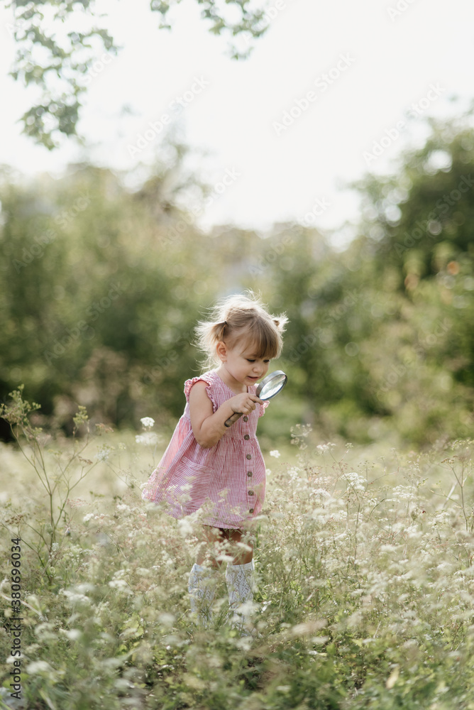 Toddler is playing with a magnifying glass and exploring Toddler is playing with a magnifying glass and exploring