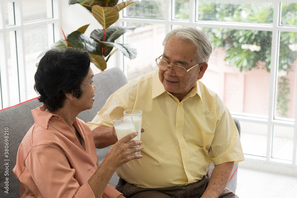 Senior Asian elderly couple in home casual outfit with happy smiling emotion sitting in living room drinking milk for healthy Senior Asian elderly couple in home casual outfit with happy smiling emotion sitting in living room drinking milk for healthy