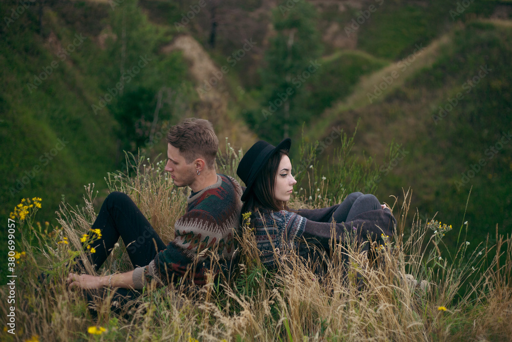 hipster guy and girl are sitting in the grass hipster guy and girl are sitting in the grass