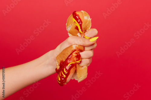 Woman's hand with painted nails squeezes hotdog photo