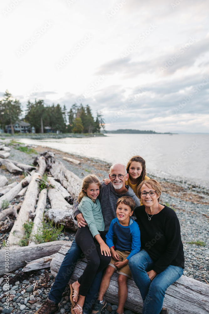Fun-loving grandparents playing with kids on beach logs. Fun-loving grandparents playing with kids on beach logs.