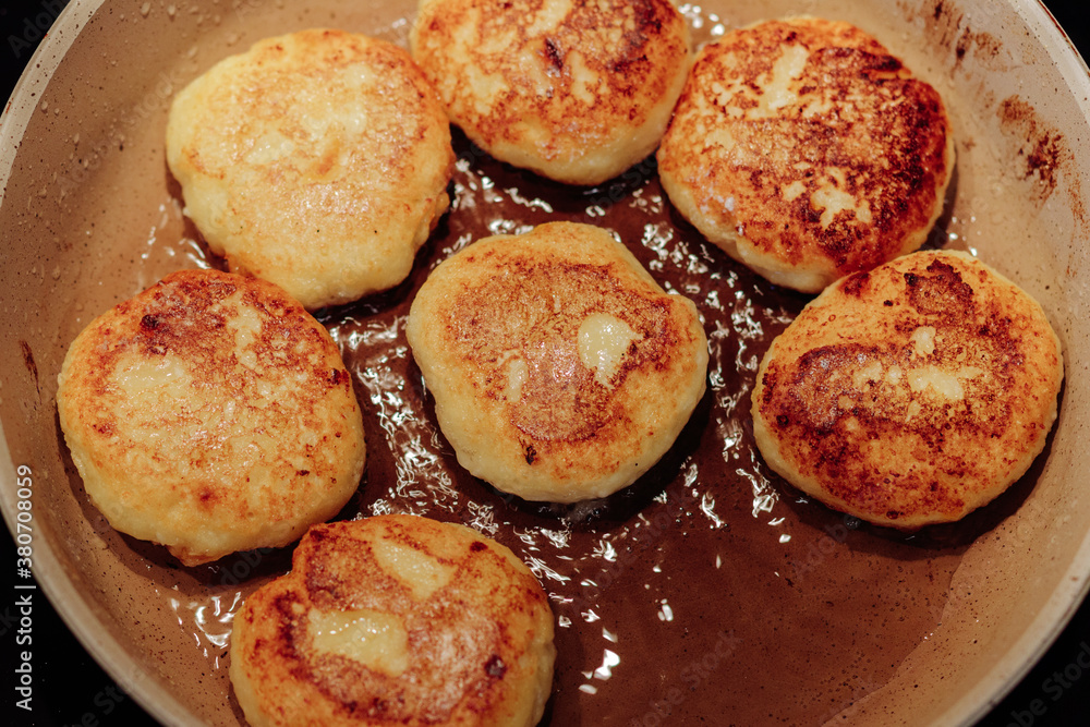 Cooking process of delicious fried syrniki close-up in the pan. Traditional in Ukraine, Belarus and Russia quark pancakes. Selective focus. Cooking process of delicious fried syrniki close-up in the pan. Traditional in Ukraine, Belarus and Russia quark pancakes. Selective focus.