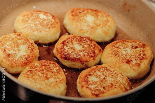 Cooking process of delicious fried syrniki close-up in the pan. Traditional in Ukraine, Belarus and Russia quark pancakes. Selective focus. © andriikomashko
