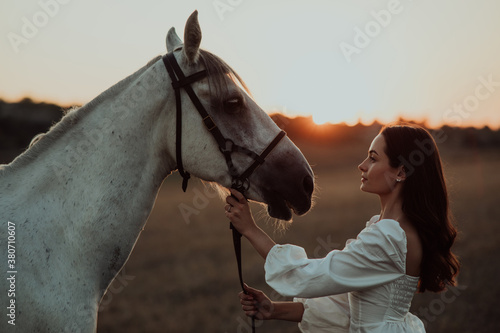 Portrait of woman near horse at sunset.