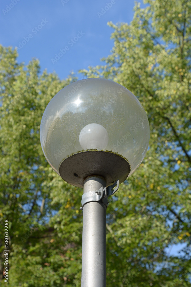 street light with condensed water on the inside and a blurred trees and sky in the background street light with condensed water on the inside and a blurred trees and sky in the background