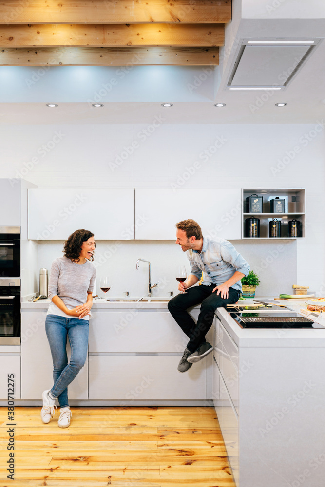 Happy couple with wine speaking in modern kitchen Happy couple with wine speaking in modern kitchen