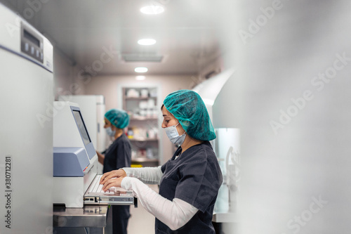 Biologists working on microscope in IVF laboratory