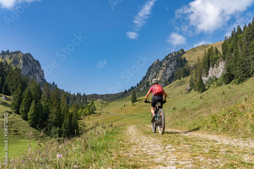 nice senior woman riding her electric mountain bike up to the Schreiber Sattel below Winterstaude summit in the Bregenzer Wald mountain range in Vorarlberg, Austria