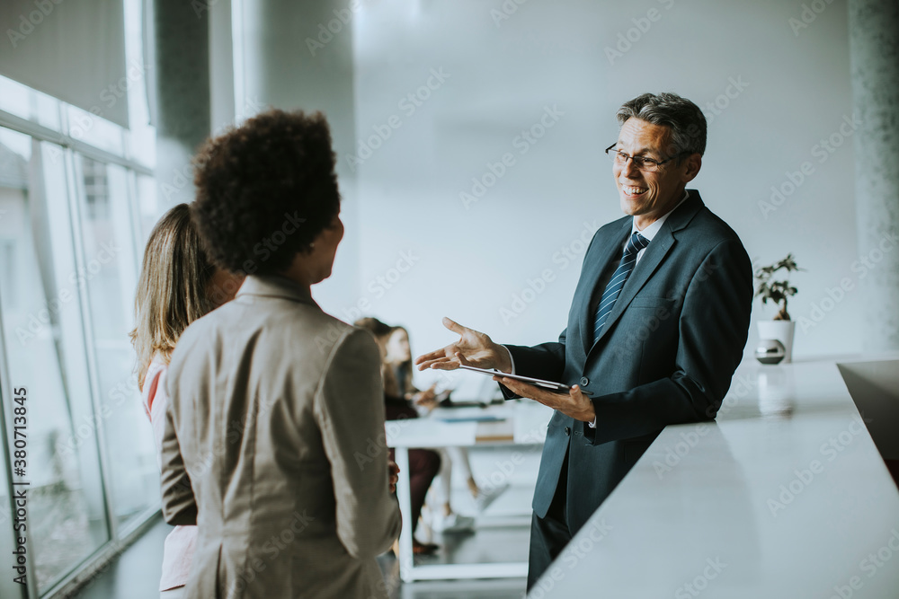 Multiethnic business people using digital tablet while standing in the office Multiethnic business people using digital tablet while standing in the office