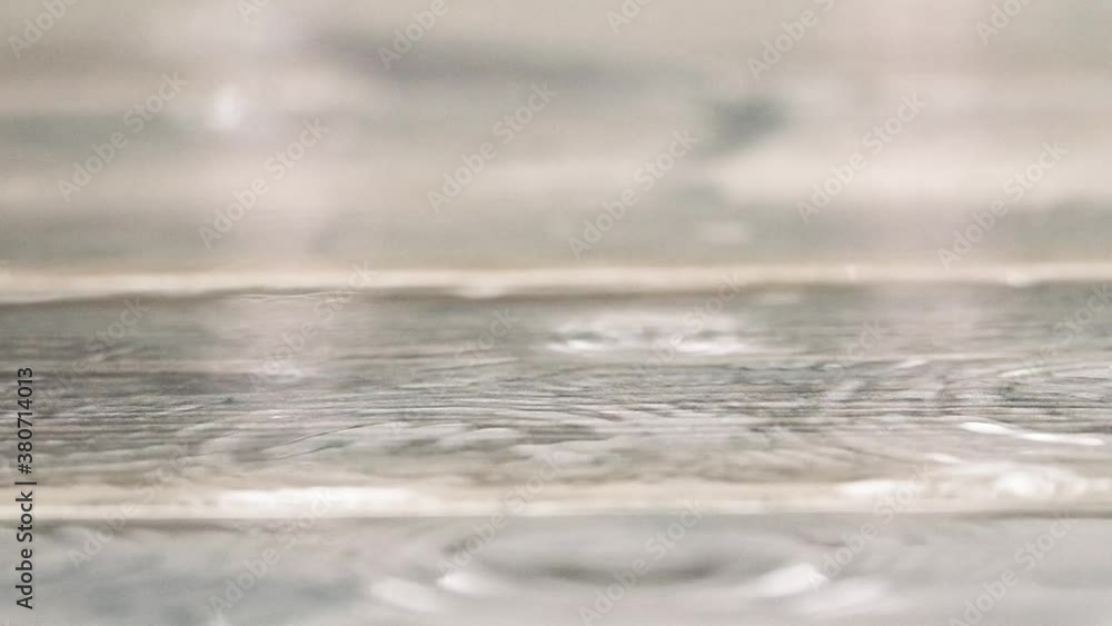 Rain drops falling on wooden board in slow motion. Rainy day background. Rain drops falling on wooden board in slow motion. Rainy day background.