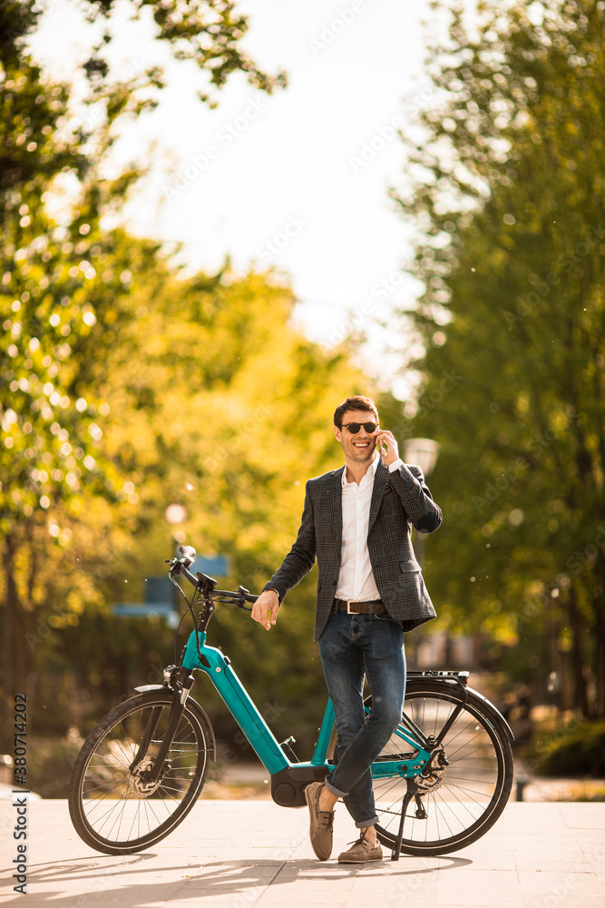 Fototapeta premium Young businessman on the ebike using mobile phone