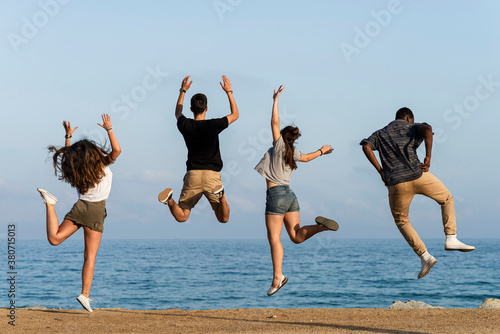 Happy friends jumping for joy by the sea photo