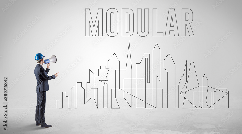 Businessman in hard hat holding blueprint with MODULAR inscription, engineering and architecture concept Businessman in hard hat holding blueprint with MODULAR inscription, engineering and architecture concept