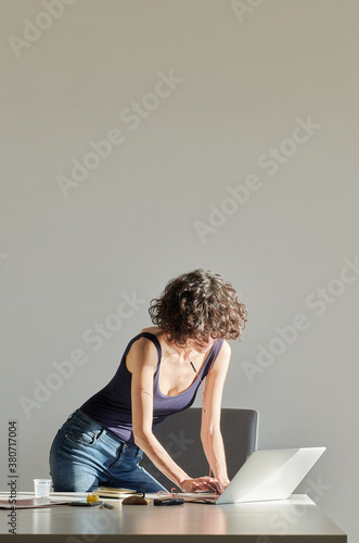 Pretty girl with earphones typing on laptop in office