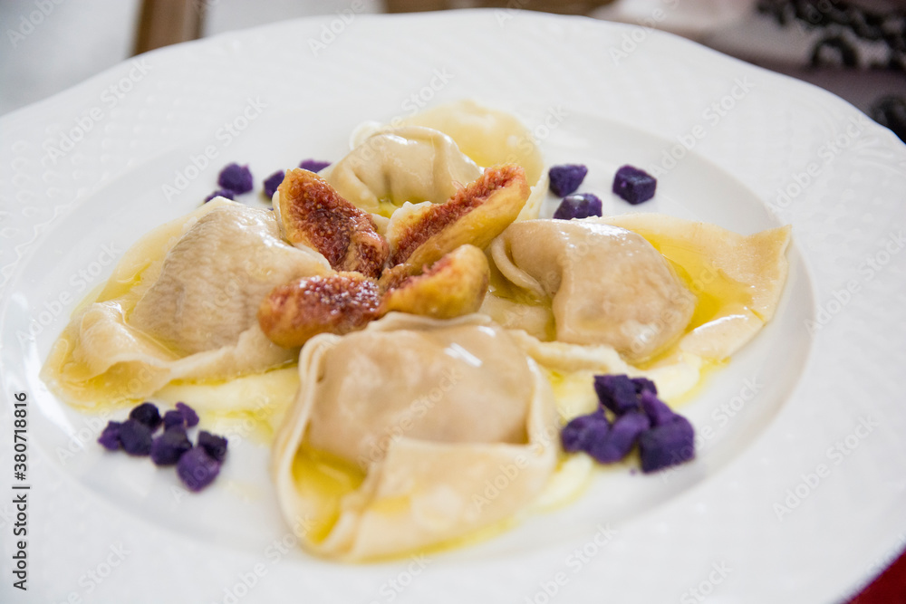 Ravioli with ricotta cheese, figs and purple sweet potatoes, served in a white plate, Italy Ravioli with ricotta cheese, figs and purple sweet potatoes, served in a white plate, Italy