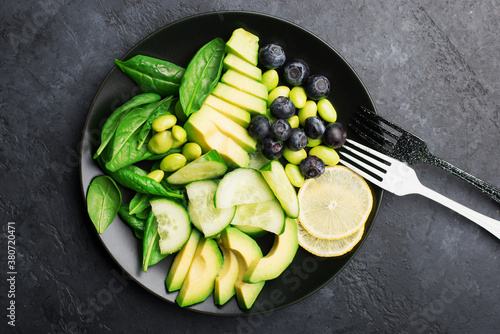 Green fruit vegetables summer detox bowl of salad. Avocado, spinach, cucumber, micro greens, blueberries one plate dish. Top View photo