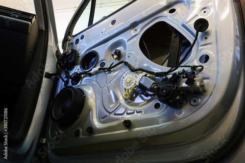 The inner lining has been removed from the door of a modern car. In the doorway you can see the wiring, the music speaker, the power window motor. Car service and electrodiagnostics Concept.  