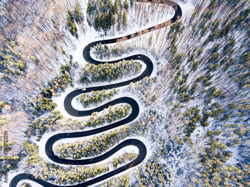 aerial view of a curvy winding road and white snow trees, winter.