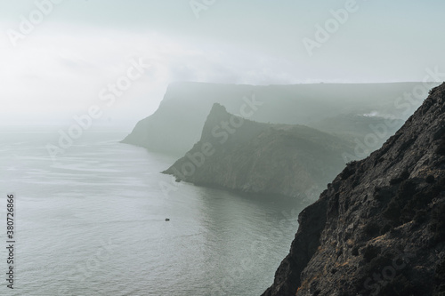 view of two rocky capes near the sea in sunset haze